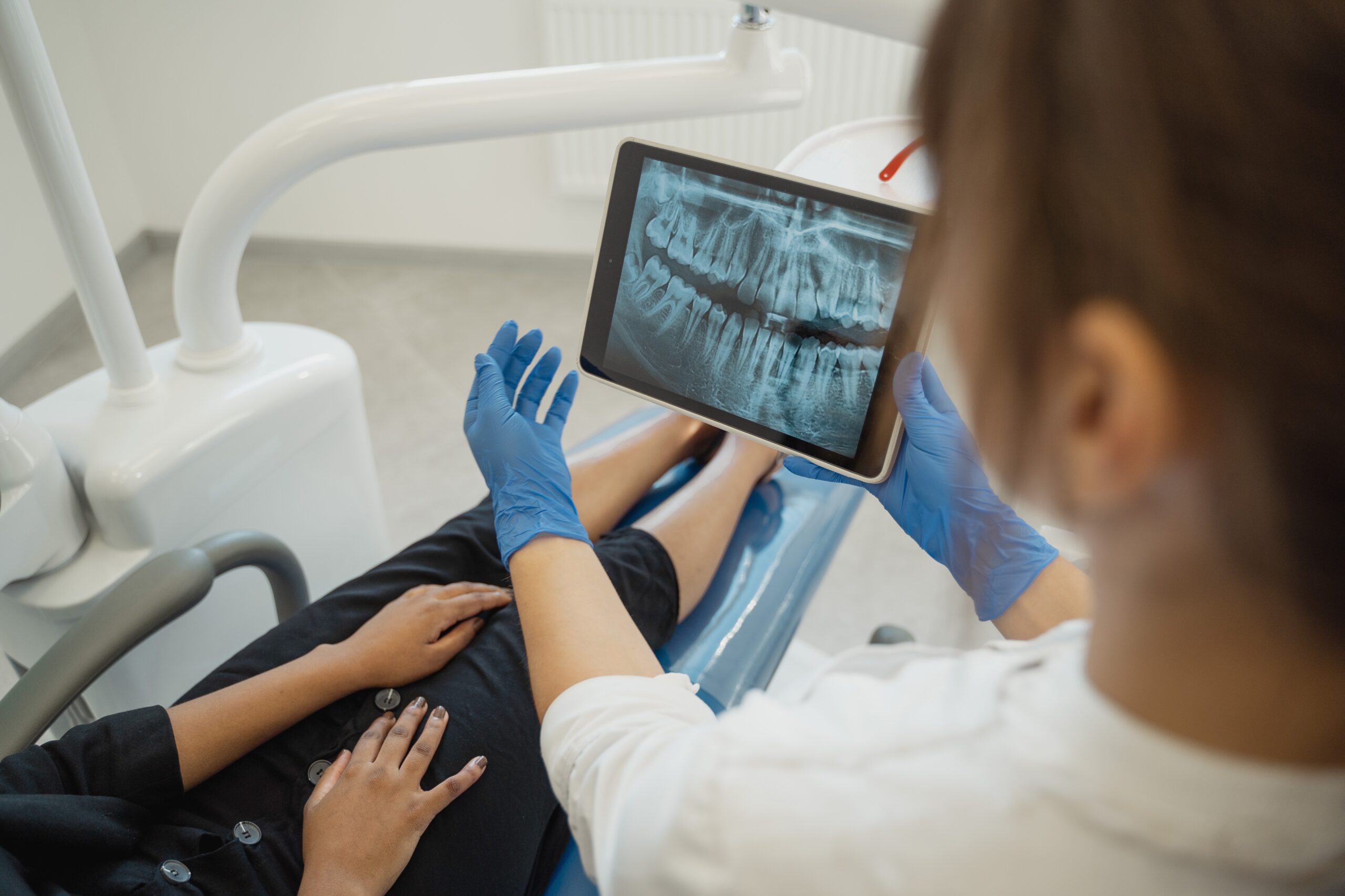 Dentist showing a dental X-ray image on a tablet to a patient during a dental checkup