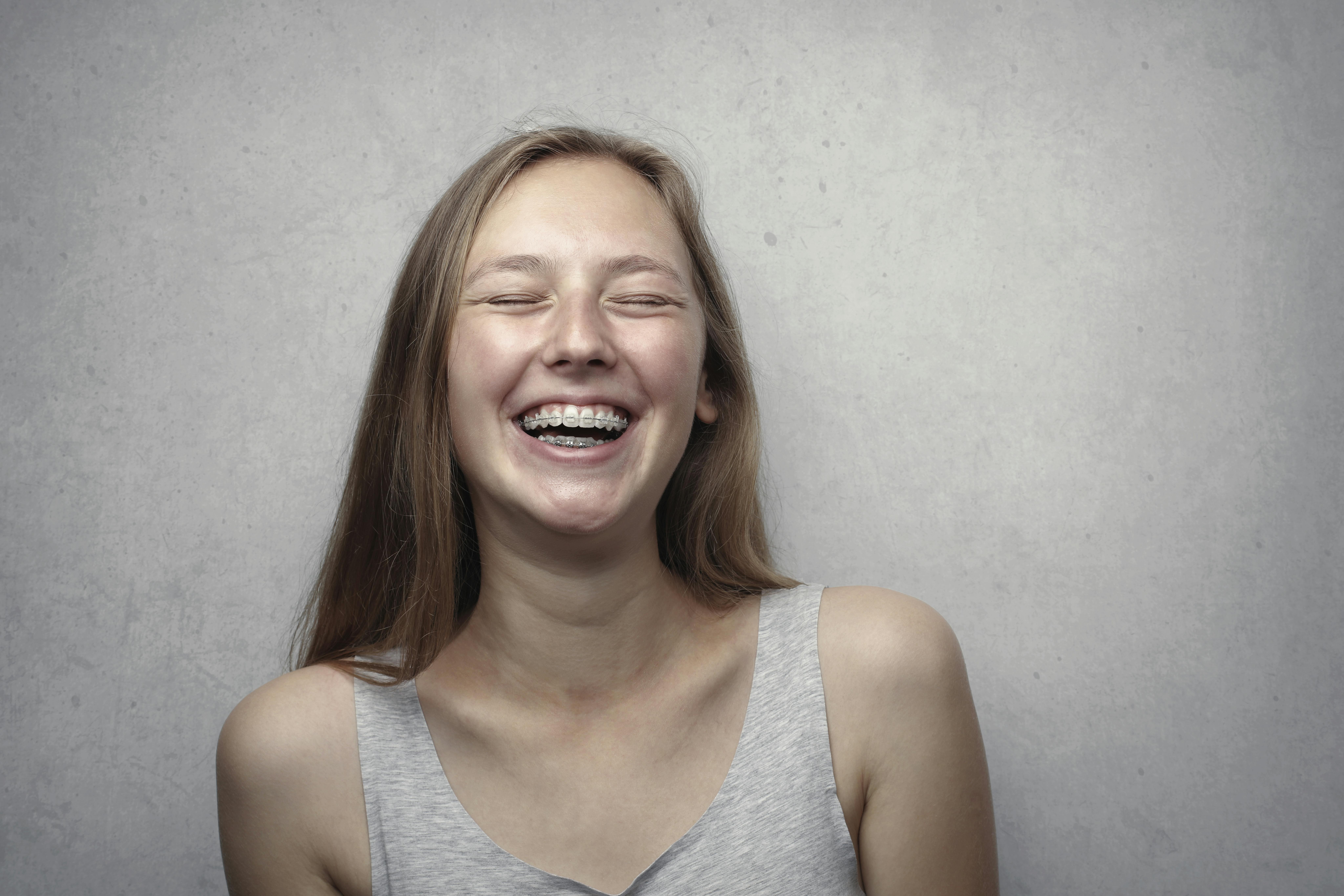 Woman with braces in grey tank top laughing