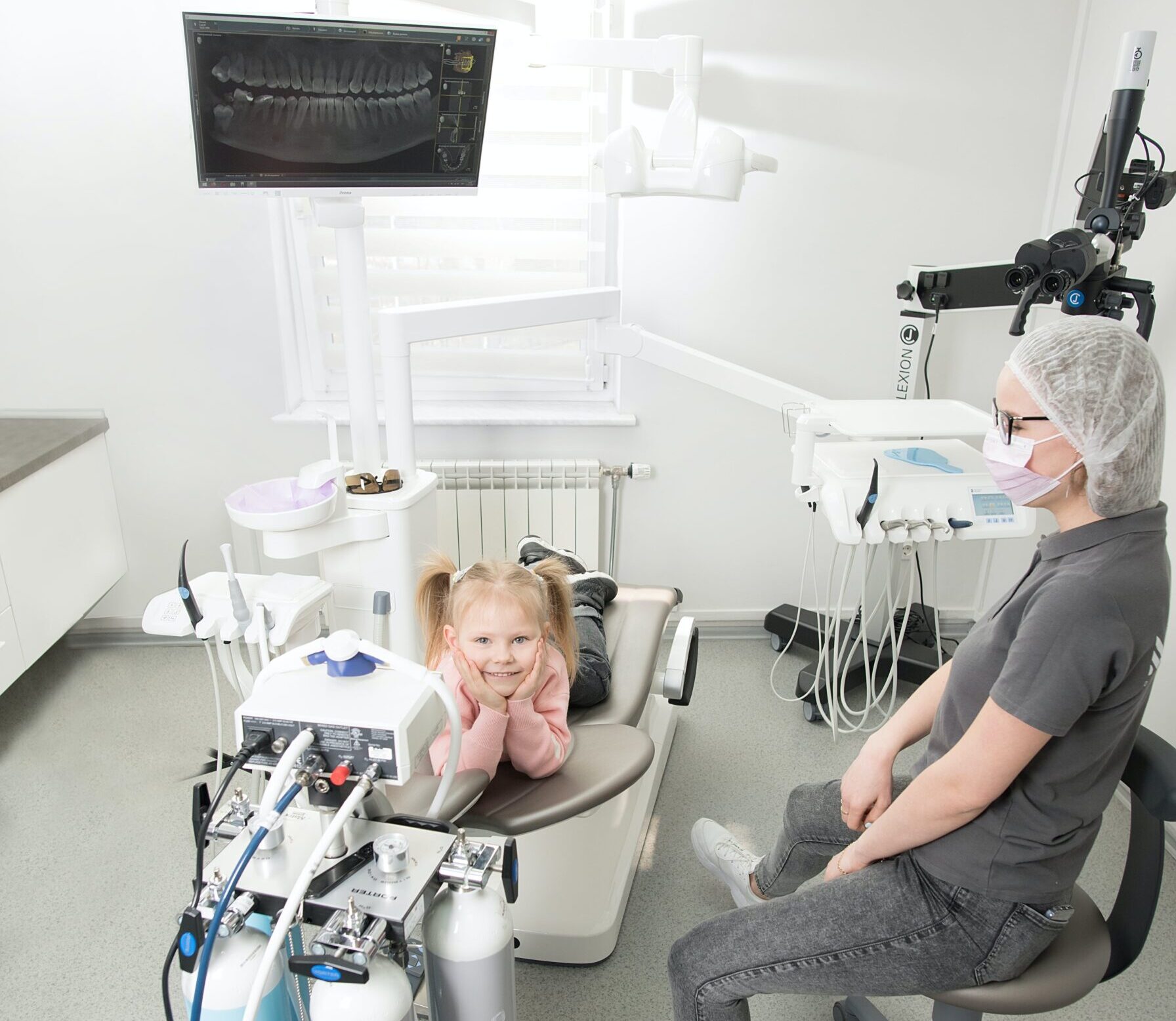 Smiling child sitting in dental chair with dentist