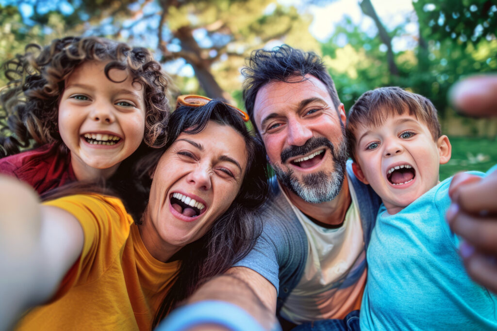 Closeup of a family taking a group selfie smiling and laughing together in an outdoor park setting