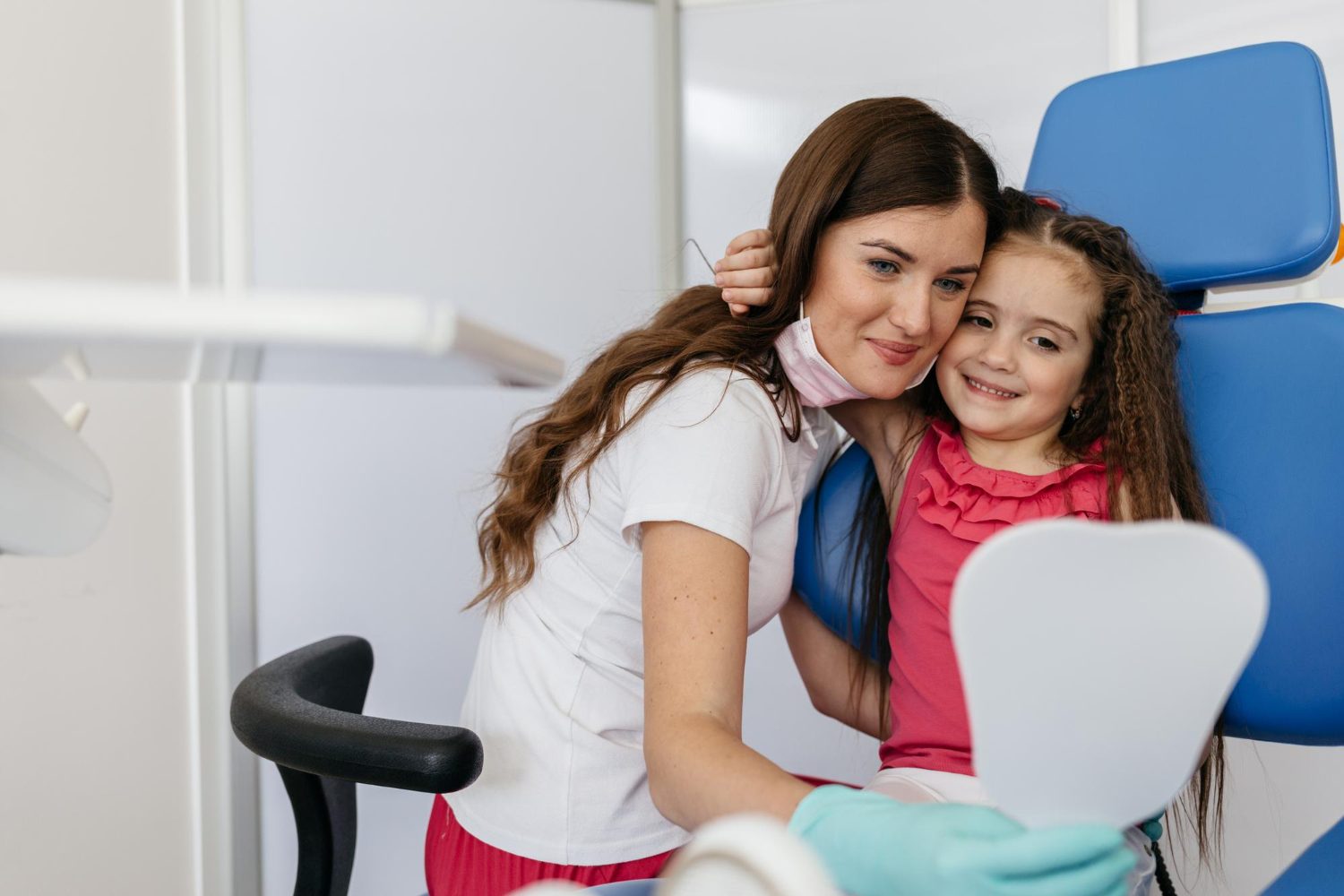 Female dentist hugging a smiling young girl in dental chair – positive pediatric dental visit at AZ Family & Kids Dental in Phoenix, Tempe, Avondale, and West Phoenix.
