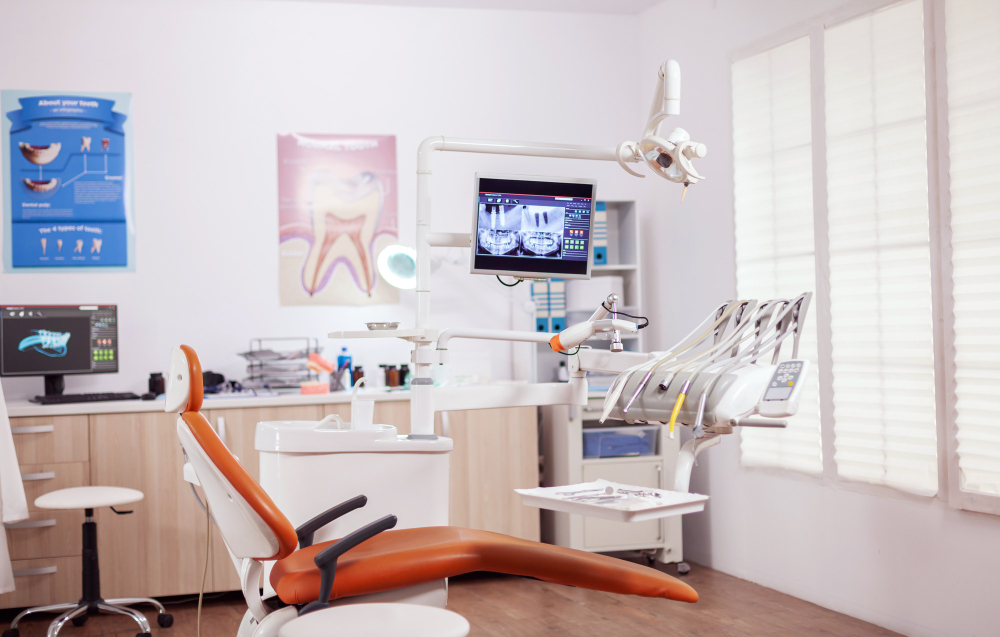 Dental chair and other accesorries used by dentist in empty cabinet. stomatology cabinet with nobody in it and orange equipment for oral treatment.